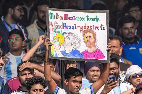 A fan holds a poster during an event as part of Argentine footballer Lionel Messi's 'G.O.A.T. India Tour 2025', at Vivekananda Yuba Bharati Krirangan (VYBK), in Kolkata.