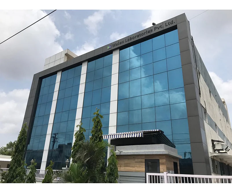 Modern office building with reflective blue glass and Welex Laboratories Pvt. Ltd. sign