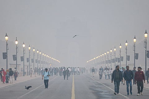 Smog engulfs Kartavya Path as people take a stroll amid low visibility, near the India Gate in New Delhi.