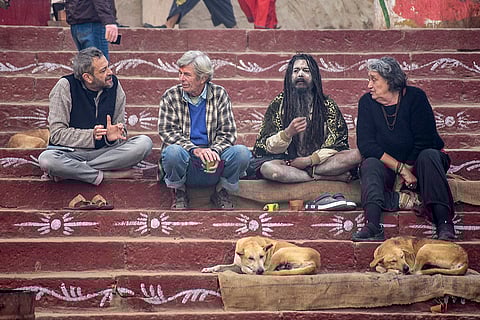Foreign tourists interact with a 'sadhu' on a winter morning, at Assi Ghat in Varanasi.