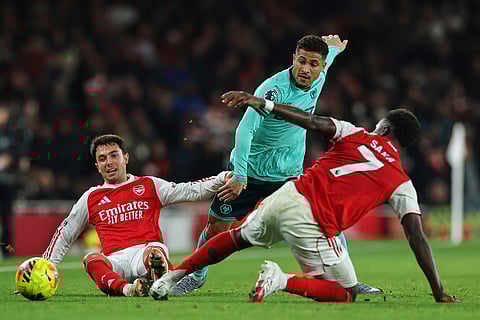 Wolverhampton Wanderers' Joao Gomes, center, is challenged by Arsenal's Martin Zubimendi, left, and Bukayo Saka during the English Premier League soccer match between Arsenal and Wolves in London.