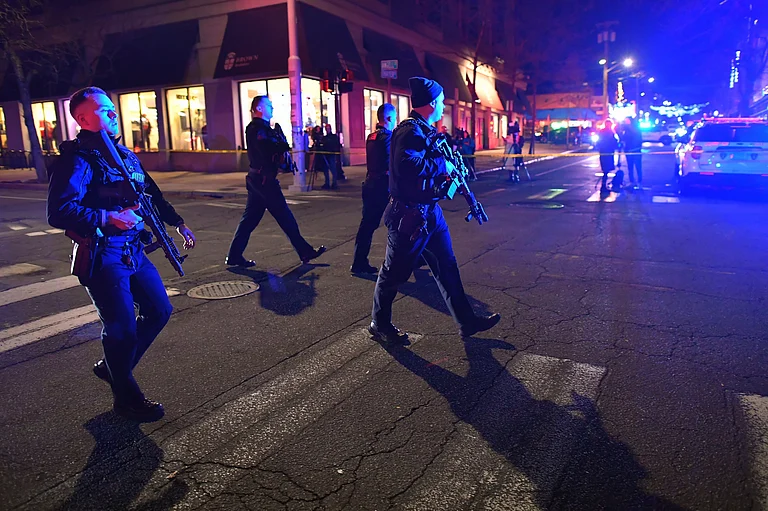 Law enforcement officials carry rifles while walking on a street in a neighborhood near Brown University in Providence, R.I., on Saturday, Dec. 13, 2025 during the investigation of a shooting. - Steven Senne