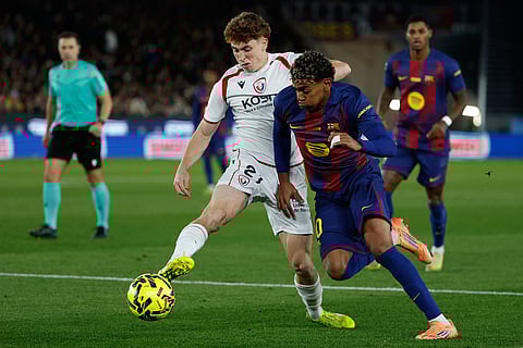 Osasuna's Victor Munoz, left, and Barcelona's Lamine Yamal fight for the ball during a La Liga soccer match between Barcelona and Osasuna in Barcelona, Spain.