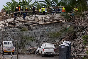 AP Photo : Rescuers search for victims after a multi-story building that was under construction collapsed on a temple below it, near the town of Verulam, north of the east coast city of Durban, South Africa, Friday, Dec. 12, 2025.