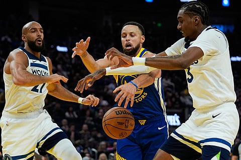 Golden State Warriors guard Stephen Curry, center, and Minnesota Timberwolves forward Jaden McDaniels, right, compete for possession of the ball during the first half of an NBA basketball game in San Francisco. 