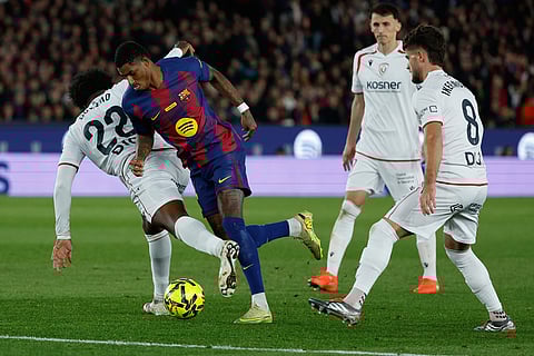 Barcelona's Marcus Rashford goes past Osasuna's Enzo Boyomo during a La Liga soccer match between Barcelona and Osasuna in Barcelona, Spain.