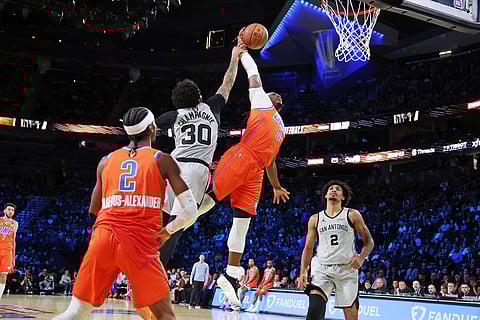 Oklahoma City Thunder guard Luguentz Dort (5) jumps to the basket near San Antonio Spurs forward Julian Champagnie (30) during the first half of an NBA Cup semifinals basketball game in Las Vegas. 