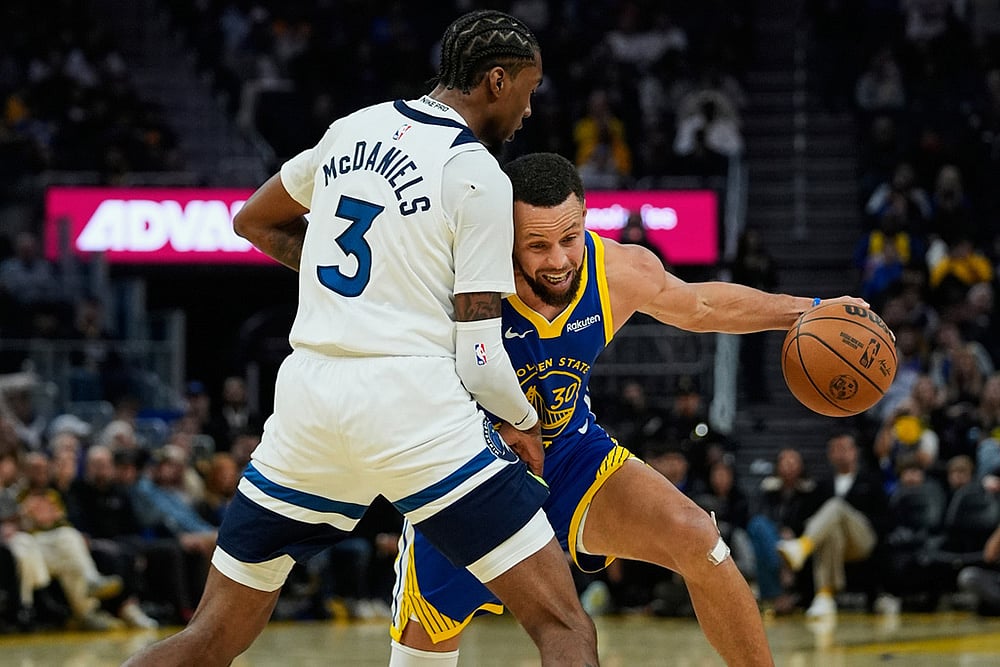 Golden State Warriors guard Stephen Curry, right, moves the ball while defended by Minnesota Timberwolves forward Jaden McDaniels during the first half of an NBA basketball game in San Francisco.  - | Photo: AP/Godofredo A. Vásquez