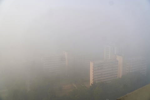 Aerial view of high-rise buildings barely visible through dense fog on a cold winter morning, in New Delhi.