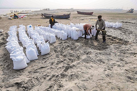 Workers fill sandbags during preparations for the 'Magh Mela 2026' festival on a cold winter day at the Sangam, in Prayagraj.