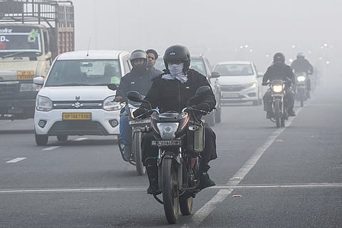 Vehicles move along a road amid fog on a cold winter morning, in New Delhi.