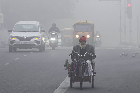 Commuters make their way on a foggy winter morning, in New Delhi.