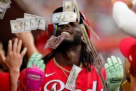 Teammates shower Cincinnati Reds' Elly De La Cruz with play money in the dugout after his two-run homer during the third inning of a baseball game against the Atlanta Braves, in Cincinnati, July 31, 2025. 