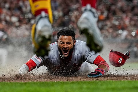 St. Louis Cardinals' Victor Scott II, bottom, scores against the San Francisco Giants on Brendan Donovan's double during the ninth inning of a baseball game, Sept. 23, 2025, in San Francisco. 