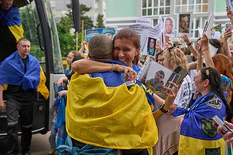 A woman hugs a soldier who came back from Russian captivity while people show photos of missing soldiers during an exchange of prisoners between Russia and Ukraine, in Chernyhiv region, Ukraine, May 25, 2025. 
