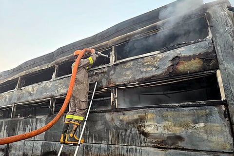 A firefighter douses a charred bus after a fog-hit pile-up involving buses and cars sparked fires on the Yamuna Expressway, in Mathura.