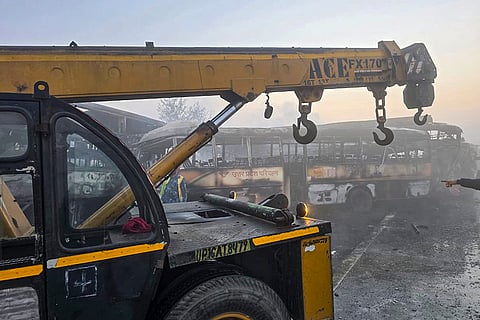 A crane is deployed to remove charred buses after a fog-hit pile-up involving buses and cars sparked fires on the Yamuna Expressway, in Mathura.
