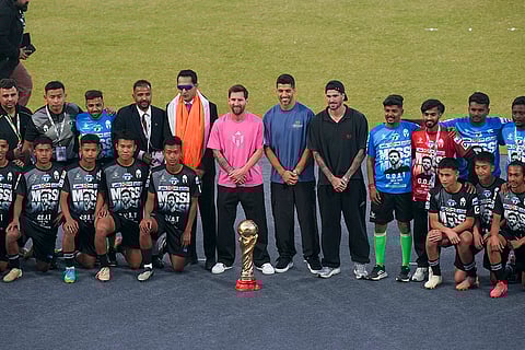 Argentine footballers Lionel Messi, in pink, Rodrigo De Paul, in black, and Uruguayan footballer Luis Suarez, in blue centre, pose for pictures during an event as part of the 'GOAT India Tour 2025', at Arun Jaitley Stadium in New Delhi.