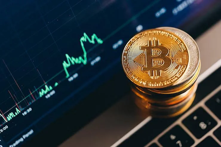 Bitcoin coins on a laptop with a trading chart