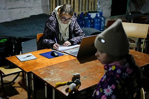 Sofia Sisa, 17, does homework in an underground shelter during an air raid alarm in Shostka, Ukraine, Oct. 16, 2025. 