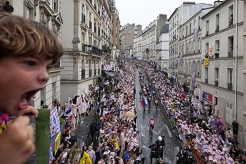 A boy shouts as the pack rides up the Montmartre hill during the last stage of the Tour de France cycling race between Mantes-la-Ville and Paris, July 27, 2025 in Paris.