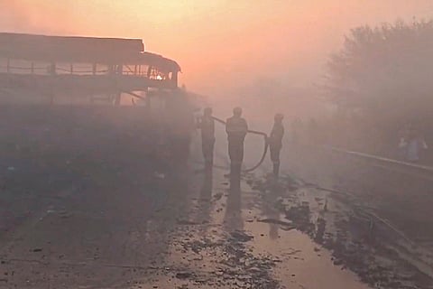 Firefighters extinguish a charred bus after a fog-hit pile-up involving buses and cars sparked fires on the Yamuna Expressway, in Mathura.