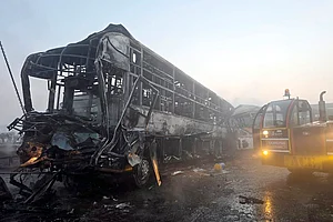 | Photo: PTI : Cranes clear the charred remains of buses after a fog-hit pile-up involving several buses and cars triggered fires on the Yamuna Expressway, in Mathura.