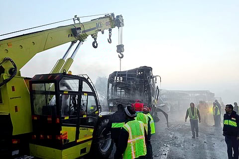 Cranes clear the charred remains of buses after a fog-hit pile-up involving several buses and cars triggered fires on the Yamuna Expressway, in Mathura.