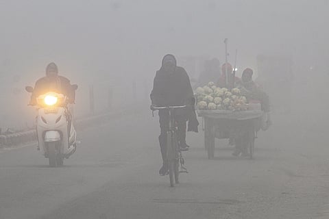 Commuters navigate through dense fog on a cold morning, in Dehradun.