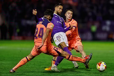 Guadalajara's Borja Diaz, center, vies for the ball with Barcelona's Eric Garcia, left, during the Copa del Rey soccer match between Guadalajara and Barcelona in Guadalajara, Spain.