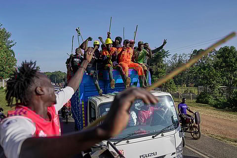 Spectators escort a truck where a bull is loaded, waving their chasing sticks and ululating, on the way to a bullfight in Kakamega, Kenya.