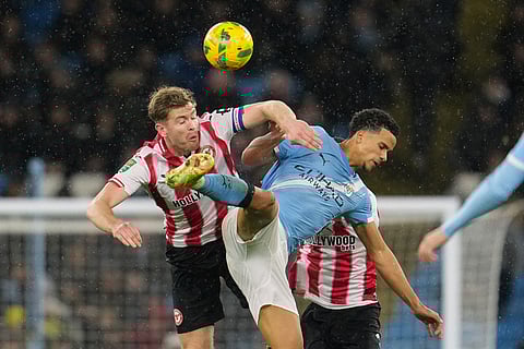 Manchester City's Divine Mukasa, right, challenges for the ball with Brentford's Nathan Collins during the English League Cup soccer match between Manchester City and Brentford in Manchester, England.
