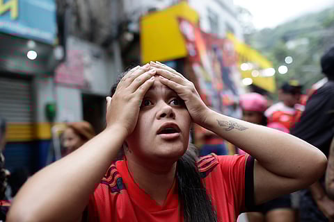 A Flamengo fan reacts after her team lost the FIFA Intercontinental Cup final soccer match against Paris Saint-Germain in Qatar, in the Rocinha favela of Rio de Janeiro.
