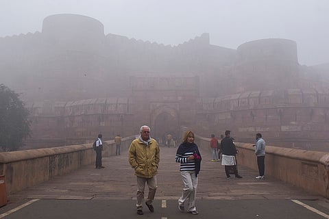 People at the Agra Fort complex as dense fog reduces visibility on a cold winter morning, in Agra, Uttar Pradesh.