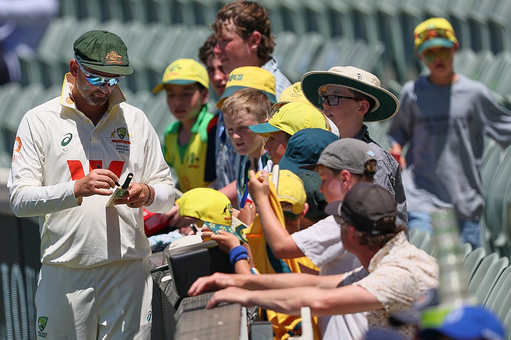 | Photo: AP/James Elsby : Australia's Nathan Lyon signs autograph to fans during play on day two of the third Ashes cricket test between England and Australia in Adelaide, Australia.