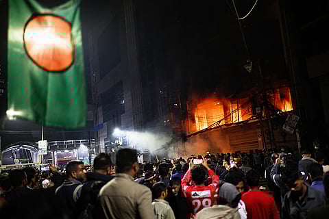 A crowd gathers near the premises of the Prothom Alo daily newspaper which was set on fire by angry protesters after news reached the country from Singapore of the death of a prominent activist Sharif Osman Hadi, in Dhaka, Bangladesh.