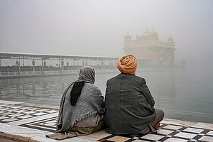 | Photo: PTI/Shiva Sharma : Devotees sit near the 'Amrit Sarovar' at Golden Temple amid dense fog, in Amritsar.