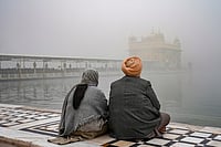 | Photo: PTI/Shiva Sharma : Devotees sit near the 'Amrit Sarovar' at Golden Temple amid dense fog, in Amritsar.