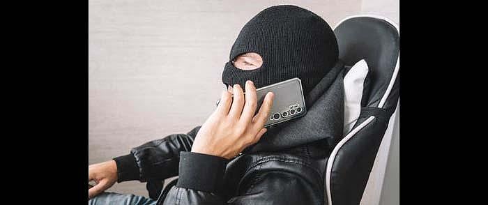 검은색 바라클라바를 쓴 사람이 의자에 앉아 통화하고 있습니다