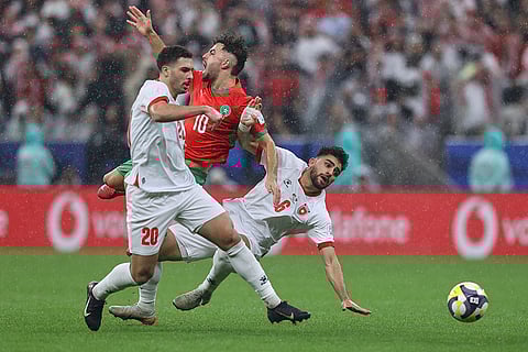 Morocco's Amin Zahzouh, center, battles for the ball with Jordan's Mohannad Abutaha, left, and Amer Jamous during to the FIFA Arab Cup final soccer match between Jordan and Morocco in Lusail, Qatar.