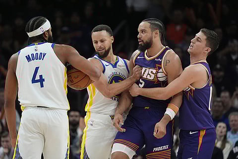 Phoenix Suns forward Dillon Brooks, second from right, is pulled away from Golden State Warriors guard Moses Moody (4) by Suns guard Collin Gillespie, right, and Warriors guard Stephen Curry (30) after Brooks fouled Moody during the second half of an NBA basketball game in Phoenix.