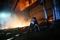 Bangladesh: NCP leader Motaleb Shikder Shot Days After Sharif Osman Hadi Killing | Photo: AP/Mahmud Hossain Opu : A girl rescues books from a shop near the premises of the Prothom Alo daily newspaper which was set on fire by angry protesters after news reached the country from Singapore of the death of a prominent activist Sharif Osman Hadi, in Dhaka, Bangladesh.