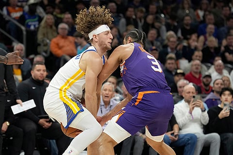 Golden State Warriors guard Brandin Podziemski, left, collides with Phoenix Suns forward Dillon Brooks (3) as they go after a loose ball during the first half of an NBA basketball game in Phoenix. 