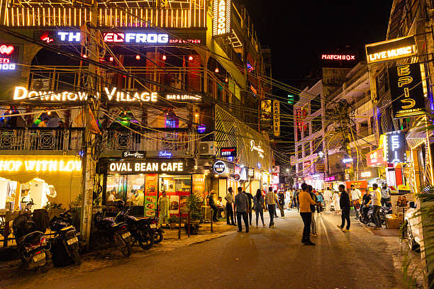 Neon-lit night street with cafes and people in Hauz Khas Village