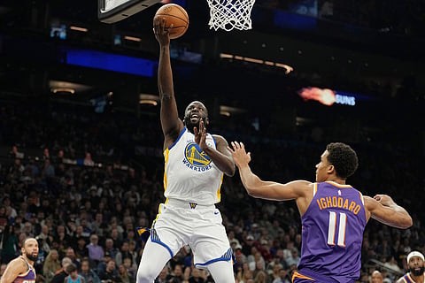 Golden State Warriors forward Draymond Green, left, drives past Phoenix Suns forward Oso Ighodaro (11) to score during the first half of an NBA basketball game in Phoenix. 