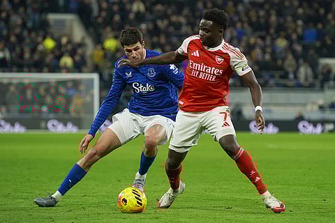 Arsenal's Bukayo Saka, right, dribbles the ball during the English Premier League soccer match between Everton and Arsenal in Liverpool, England.