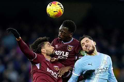 West Ham's Lucas Paqueta, left, and teammate West Ham's Soungoutou Magassa, center, jump to head the ball with Manchester United's Matheus Cunha during the English Premier League soccer match between Manchester City and West Ham United in Manchester, England.