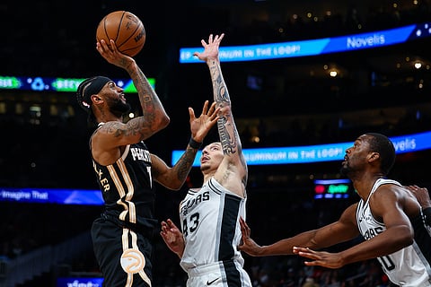 Atlanta Hawks guard Nickeil Alexander-Walker, left, shoots over San Antonio Spurs forward Lindy Waters III, center, during the first half of an NBA basketball game in Atlanta. 