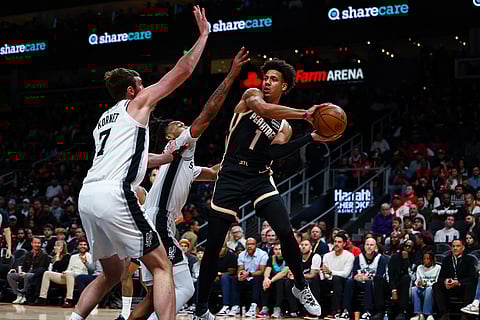 Atlanta Hawks forward Jalen Johnson (1) looks to pass the ball aound San Antonio Spurs center Luke Kornet (7) during the first half of an NBA basketball game, in Atlanta. 