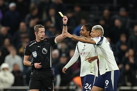 Referee John Brooks, left, shows a yellow card to Tottenham's Richarlison, right, during the English Premier League soccer match between Tottenham and Liverpool in London.